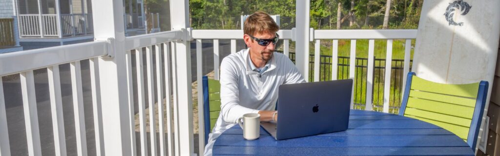 Man sitting in seating area on front porch while on computer